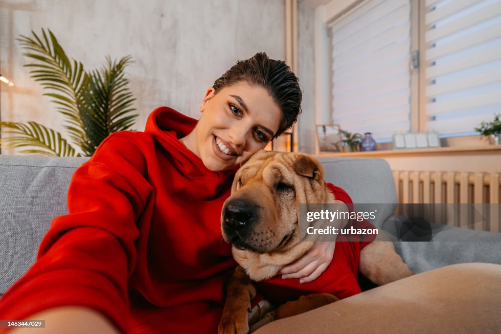 Mulher jovem tirando uma selfie com seu cachorro em casa