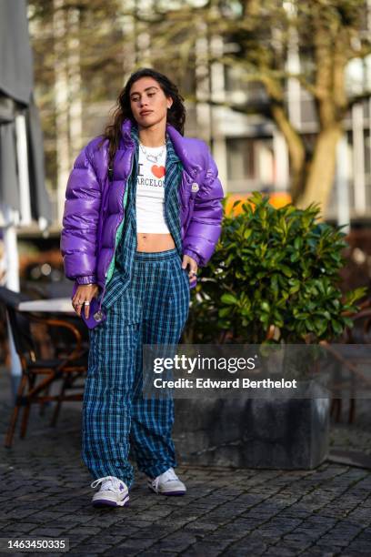 Guest wears a black triangular pattern earrings from Prada, earrings, a white with black and red print pattern cropped top, a blue and black...