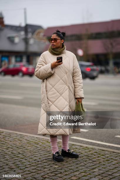 Guest wears brown sunglasses, a khaki wool scarf, a beige quilted / belted long coat, pale pink wool socks, a khaki fluffy handbag, black shiny...