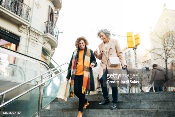two senior woman walking down stairs - barcelona shopping stock pictures, royalty-free photos & images