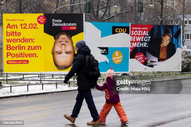 Man and child walk past banners with an election campaign posters that show German Free Democrats lead candidate Sebastian Czaja, German Christian...