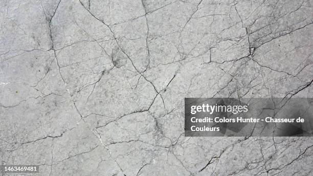 gray and cracked weathered stone wall lit by the sun in paris - ひびが入った ストックフォトと画像