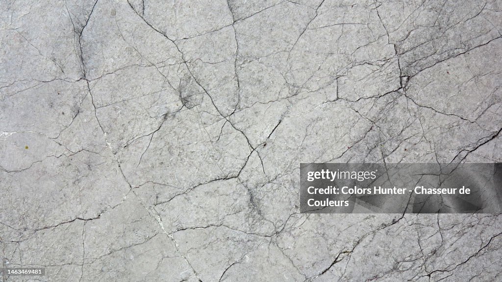 Gray and cracked weathered stone wall lit by the sun in Paris