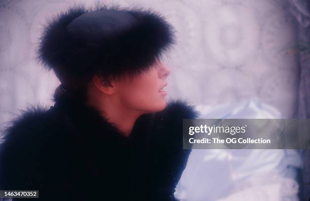 Profile portrait of American model and actress Sheila Kennedy in a black fur hat and matching jacket, New York, New York, September 1983. The photo...