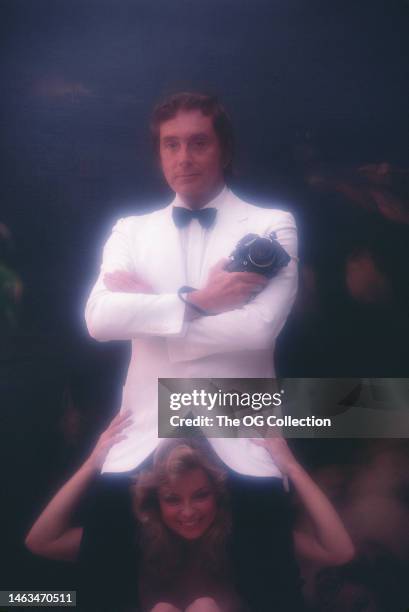 Portrait of American publisher Bob Guccione , a camera in his hand, and model & actress Sheila Kennedy between his legs, New York, New York, August...