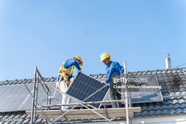 two workers installing solar panel on roof at new home - underhållstekniker bildbanksfoton och bilder