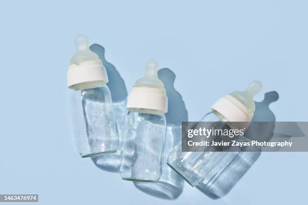 three glass feeding bottles on blue background - milchflasche stock-fotos und bilder