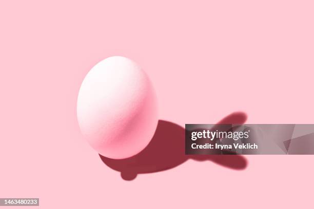 white easter egg with shadow in shape of easter bunny in viva magenta color of the 2023 year on pastel pink background. - osterhase stock-fotos und bilder