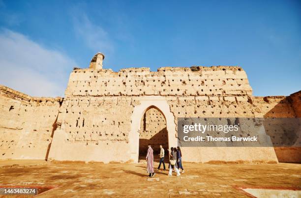 extreme wide shot of family exploring el badi palace with tour guide - maroc school stock-fotos und bilder