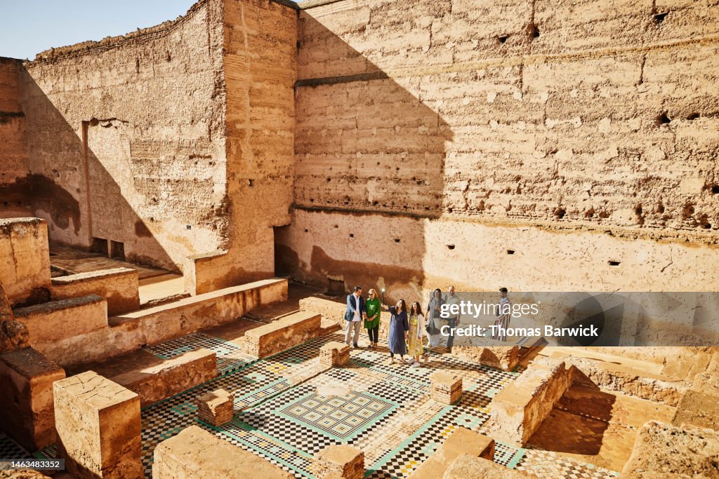 Wide shot of group of tourists exploring El Badi Palace with tour guide