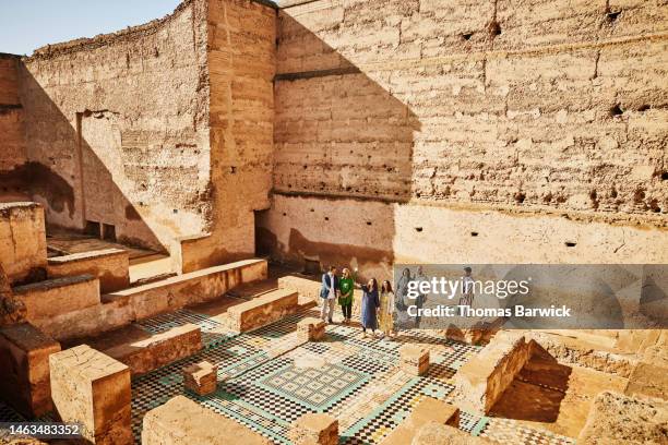 wide shot of group of tourists exploring el badi palace with tour guide - free mosaic patterns stock-fotos und bilder