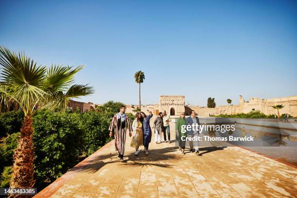 wide shot of tour guide leading tourist on tour of el badi palace - maroc school photos et images de collection