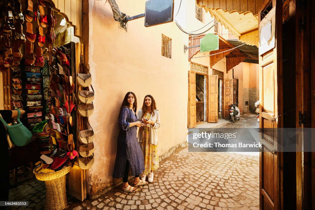 Wide shot of sisters exploring the souks of Marrakech during vacation