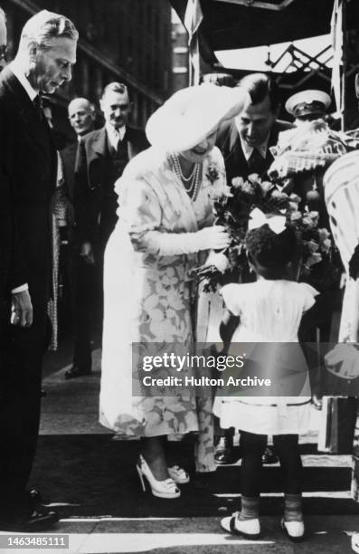 Queen Elizabeth accepts a bouquet from 3-year old Nigerian girl Ayo Shonekan when the Queen and King George VI visit a Colonial Exhibition, London,...