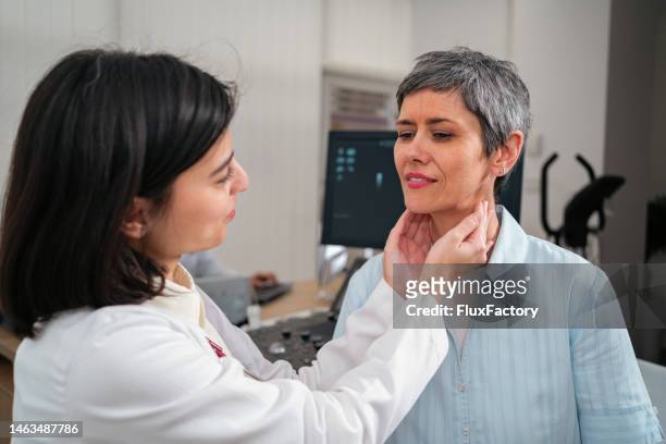 female doctor palpating female patient thyroid gland - human gland stockfoto's en -beelden