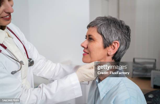 femme médecin palpant la glande thyroïde d’une patiente - système endocrinien photos et images de collection