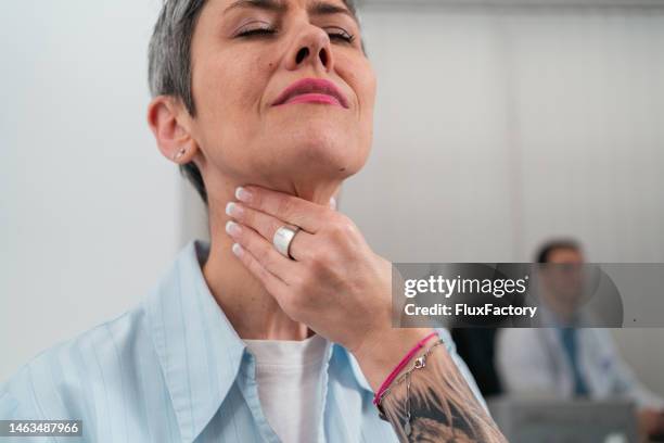 woman touching her sore throat, while making a grimace because of the pain - old woman tattoos stock pictures, royalty-free photos & images