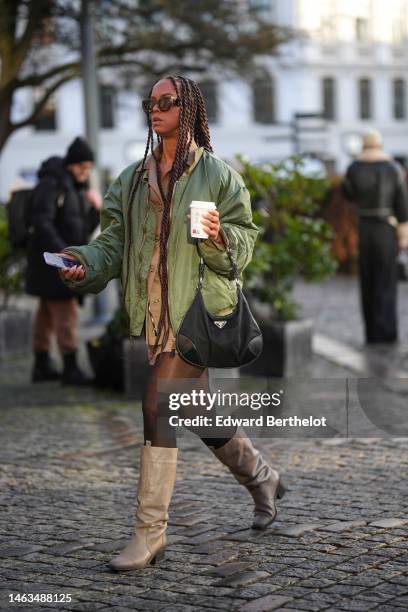 Guest wears brown sunglasses, gold chains pendant necklaces, a brown shirt from Munthe, a green oversized bomber coat, a black nylon handbag from...