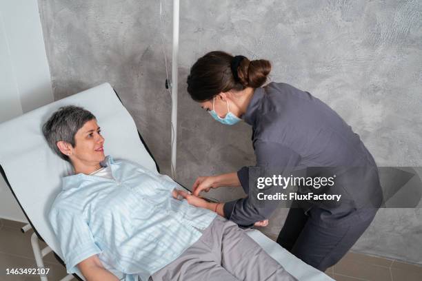 female nurse adjusting iv drip on a senior female patient - vitamin iv stock pictures, royalty-free photos & images