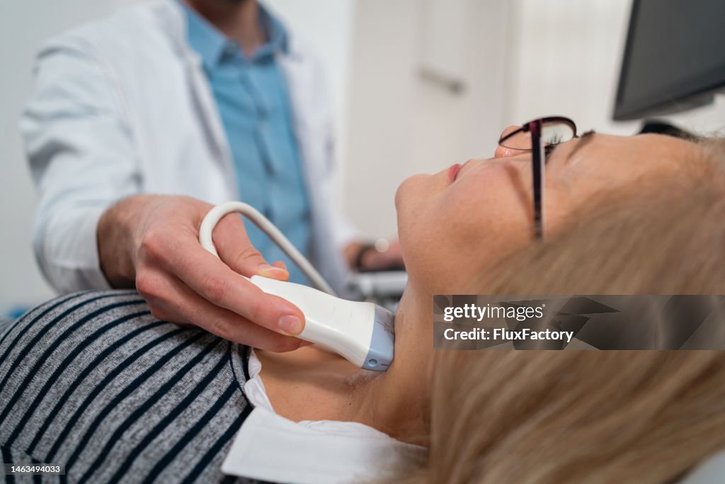 Endokrinologe führt Ultraschall der Schilddrüse bei einer älteren Patientin durch
