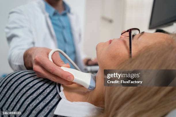 endocrinologist doing ultrasound of thyroid gland on a senior female patient - ultraljud bildbanksfoton och bilder
