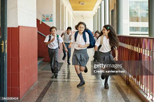 smiling classmates racing in school hallway - private school uniform stock pictures, royalty-free photos & images