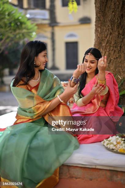 two beautiful women in saris admiring each other's bangles - indian jewellery stock pictures, royalty-free photos & images