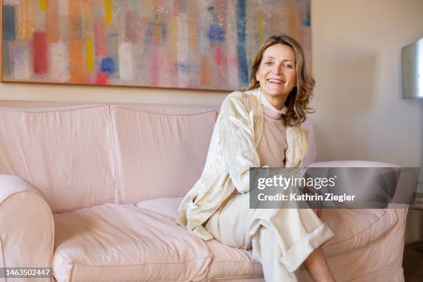 portrait of beautiful mature business woman sitting on sofa - women pastel stock pictures, royalty-free photos & images