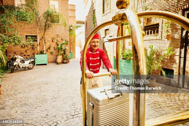 Wide overhead shot of bellman moving guests luggage in hotel courtyard