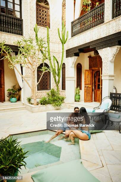 Wide shot of couple relaxing at edge of plunge pool at luxury hotel