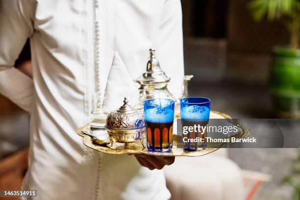close up shot of wait holding mint tea service on tray in luxury hotel - moroccan tea cups photos et images de collection