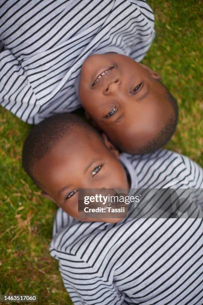 smile, carefree and portrait of boys on grass for playing, bonding and relax in nature of morocco. happy, playful and face of african twins on a field in the countryside for sunshine and happiness - twins stock pictures, royalty-free photos & images