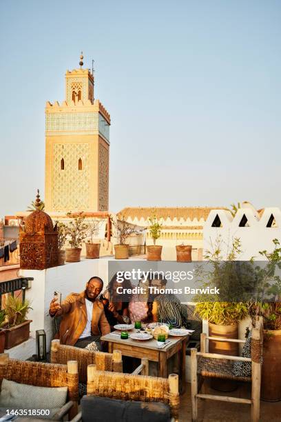 wide shot of friends taking selfie at rooftop restaurant in marrakech - rooftop dining foto e immagini stock