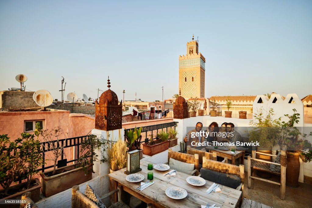 Wide shot of couple taking selfie at rooftop restaurant in Marrakech