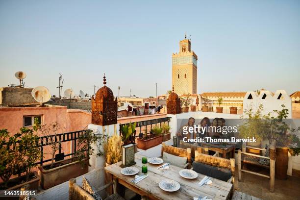 wide shot of couple taking selfie at rooftop restaurant in marrakech - travel stock-fotos und bilder