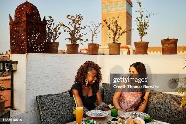 wide shot of smiling friends dining at rooftop restaurant in marrakech - rooftop dining foto e immagini stock