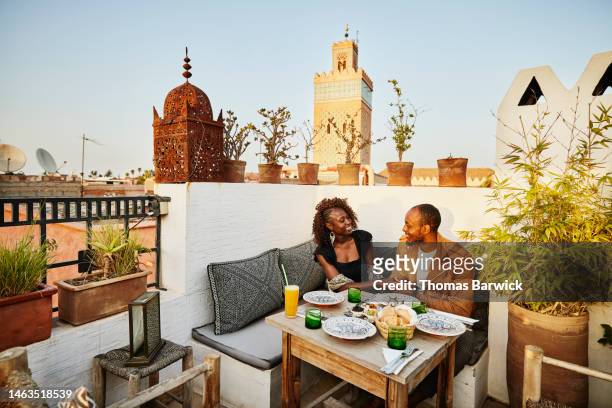wide shot of smiling couple dining at rooftop restaurant in marrakech - upper class stock pictures, royalty-free photos & images
