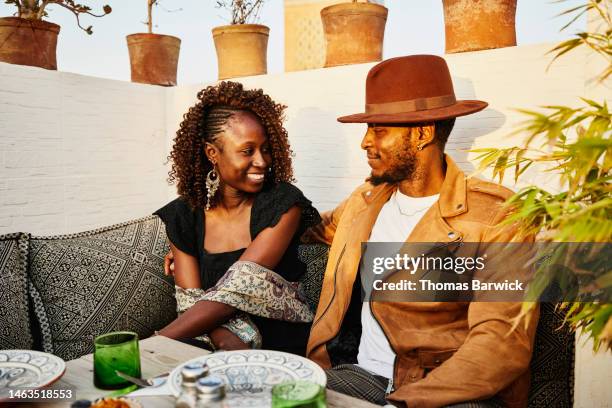 medium shot of smiling couple dining at rooftop restaurant in marrakech - black couple date stockfoto's en -beelden