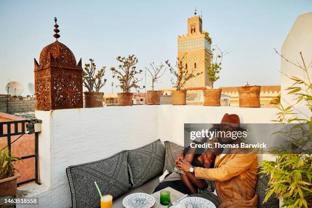 wide shot of couple enjoying sunset dinner at rooftop restaurant in marrakech - black couple dining stockfoto's en -beelden