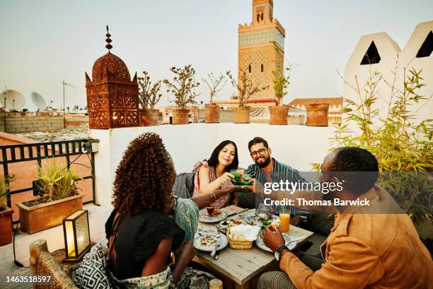 wide shot of friends toasting with tea while dining at rooftop restaurant - rooftop dining foto e immagini stock