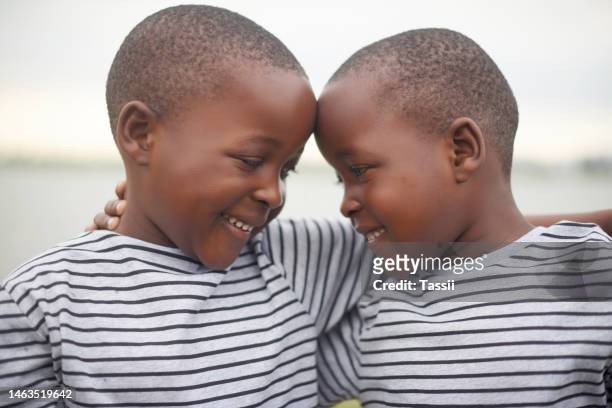 love, bond and boy twins hugging for brotherhood, care and friendship while on summer vacation. happiness, excited and african children embracing outdoor by the lake while on holiday or weekend trip. - cute twins stockfoto's en -beelden