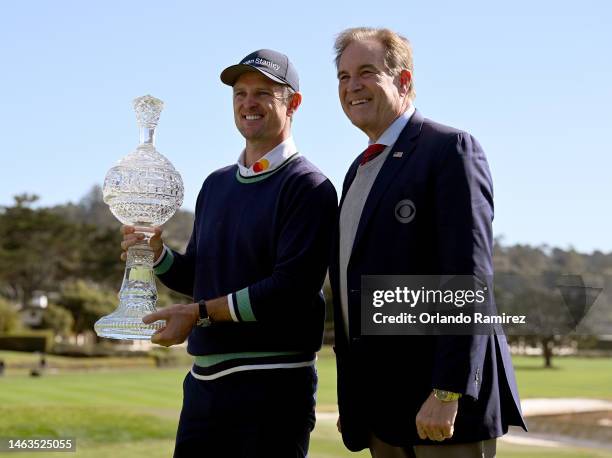 Justin Rose of England poses with the trophy and commentator Jim Nantz on the 18th hole during the continuation of the final round of the AT&T Pebble...