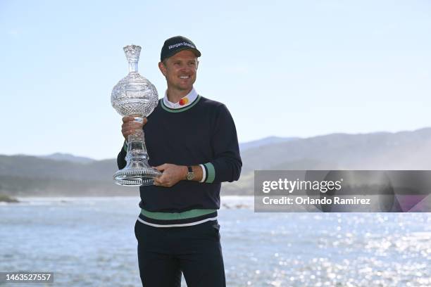 Justin Rose of England poses with the trophy on the 18th hole after victory during the continuation of the final round of the AT&T Pebble Beach...