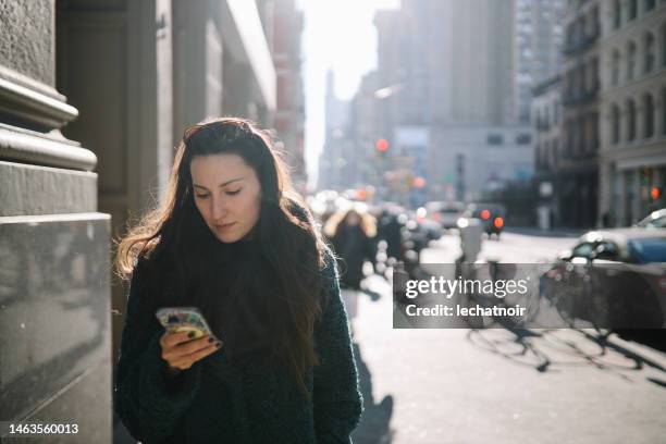 commuter checking apps on the streets of nyc - walk new york stock pictures, royalty-free photos & images