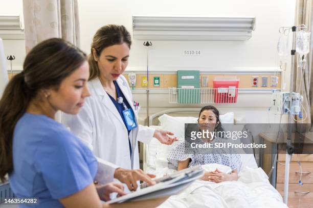 while talking to patient, doctor checks medical test results - er doctor stock pictures, royalty-free photos & images