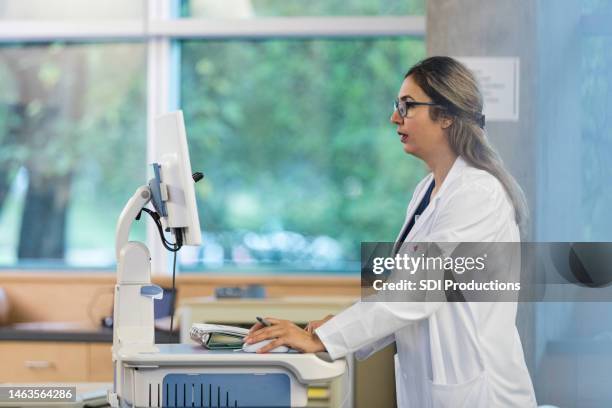 il medico utilizza il pc desktop nel reparto ospedaliero per aggiornare i record - cartella clinica elettronica foto e immagini stock