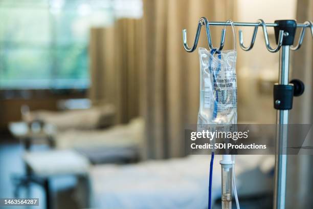 focus on iv bag and stand in empty hospital ward - hospital bed with iv stock pictures, royalty-free photos & images