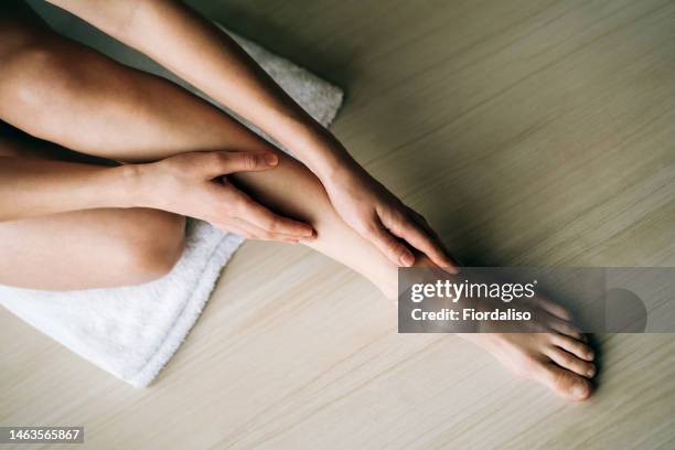 woman massaging her legs - female feet stockfoto's en -beelden