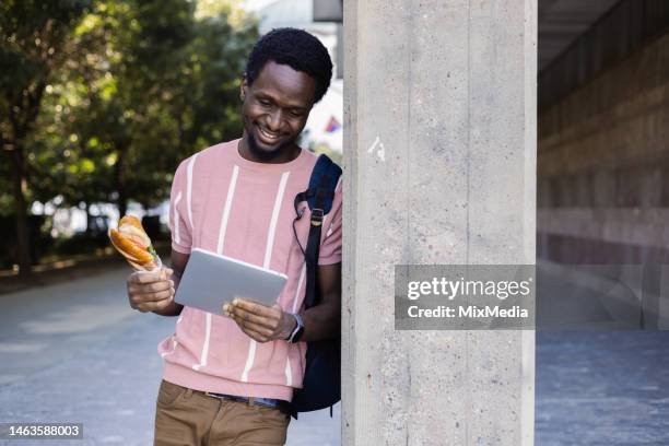 african student eating and using smartphone on the move - snacking on the go stock pictures, royalty-free photos & images