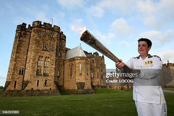 In this handout image provided by LOCOG, Torchbearer Lewis Denny carries the Olympic Flame through the grounds of Alnwick Castle, which was used in...